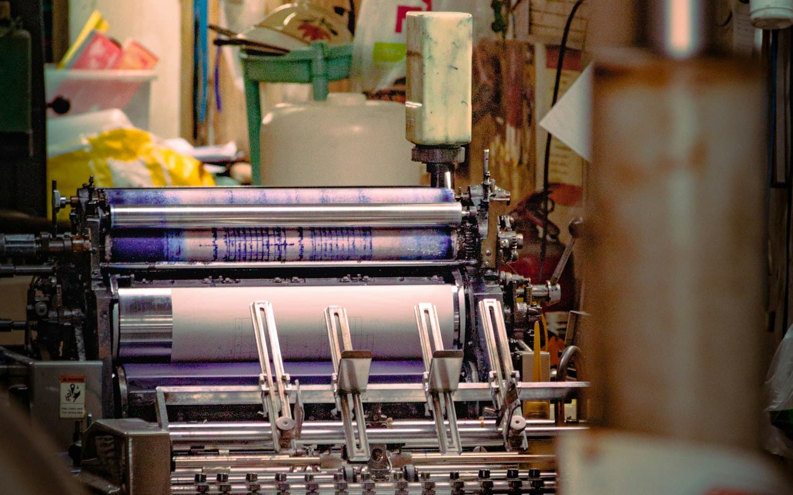 An offset printing press with purple-inked rollers in a print shop